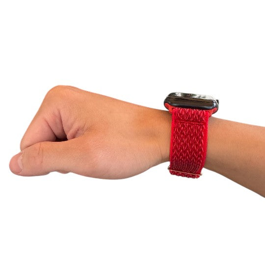 A hand wearing a red woven nylon Apple Watch band designed for sleeping, showcasing comfort and style for a good night's rest.