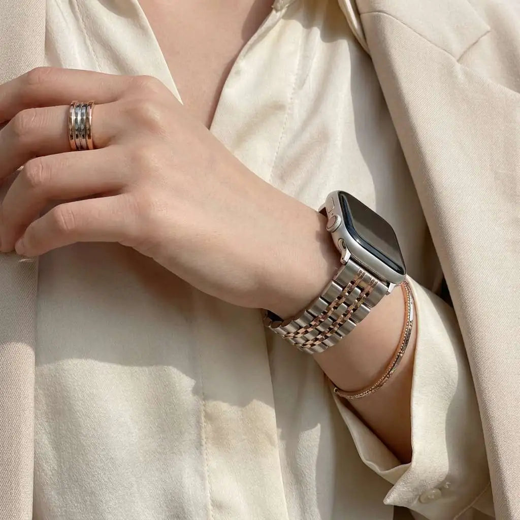 Anhem Allure Steel Strap, a two-tone stainless steel Apple Watch band with triple-link design on a woman's wrist.
