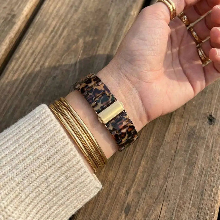 Anhem Amber Resin Apple Watch strap with a tortoiseshell pattern worn on a wrist with gold stacked bracelets.