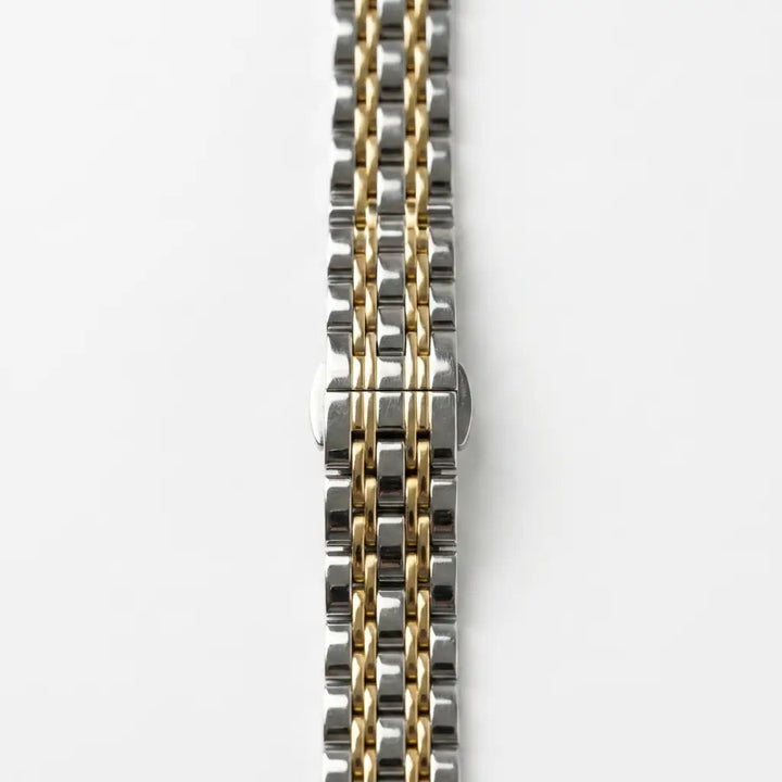 Anhem Glam Steel two-tone silver and gold slim link Apple Watch band on a white background.