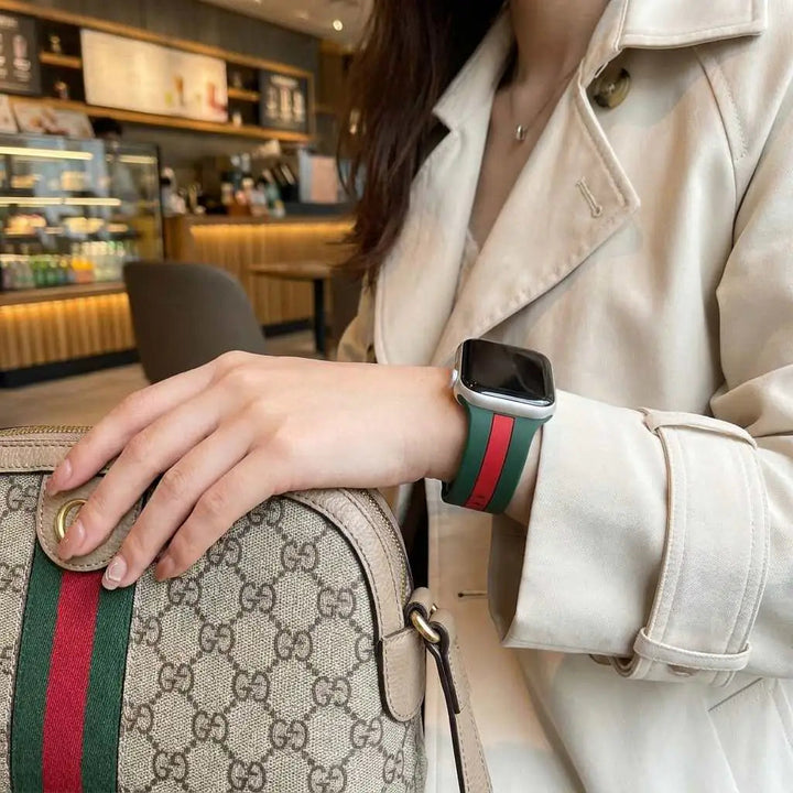 Anhem Pepi two-tone green and red silicone sport band on an Apple Watch worn by a woman in a beige trench coat