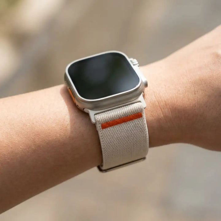 Anhem Ultra Nylon elastic watch band in beige with orange accent worn on a wrist with an Apple Watch Ultra