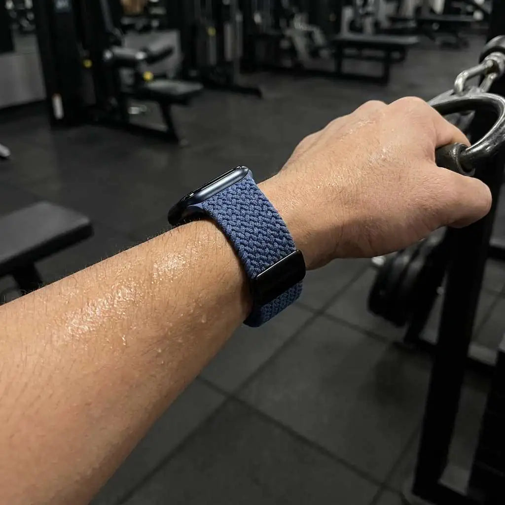 Person exercising in a gym with a blue woven apple watch on wrist