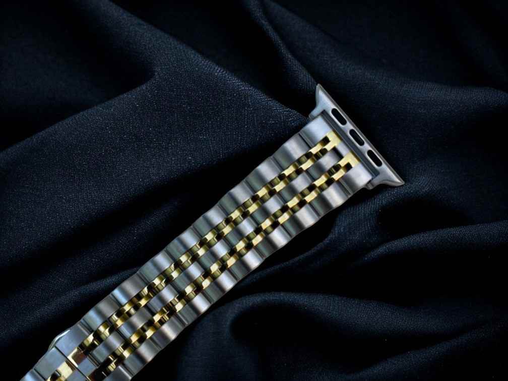 anhem allure silver and gold metal apple watch band laid flat on cloth